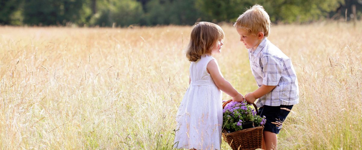 Little boy helping little girl with the basket of flowers